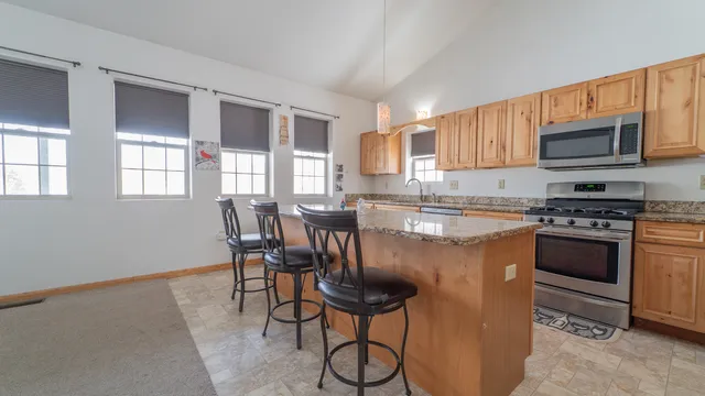 a kitchen with stainless steel appliances granite countertop a stove a sink dishwasher a microwave oven and a refrigerator with wooden cabinets