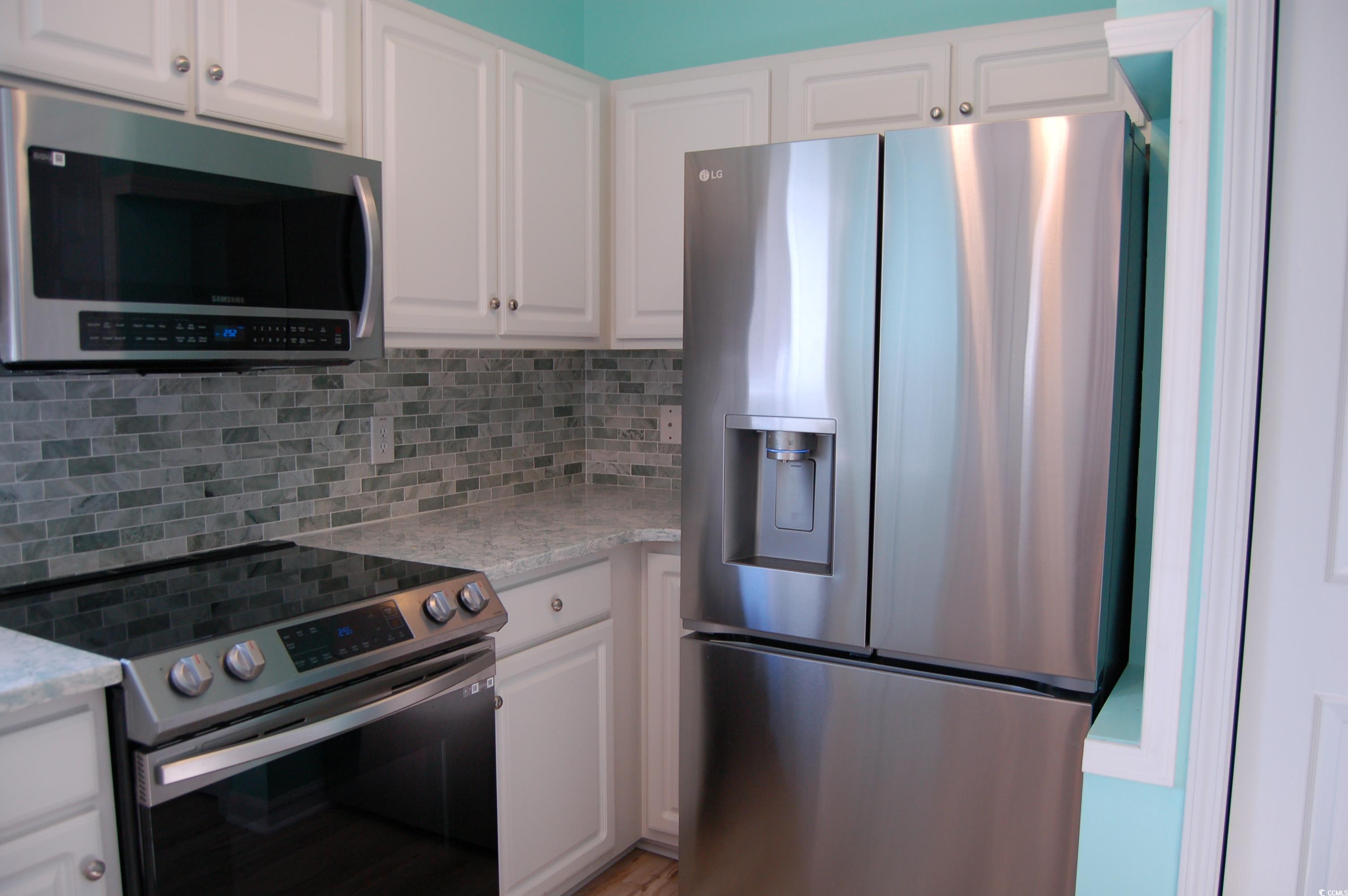 1537 Lanterns Rest Road, Unit 203 Myrtle Beach, SC 29579 - Photo 16 of 35 Kitchen featuring appliances with stainless steel finishes, white cabinetry, decorative backsplash, and light quartz counters
