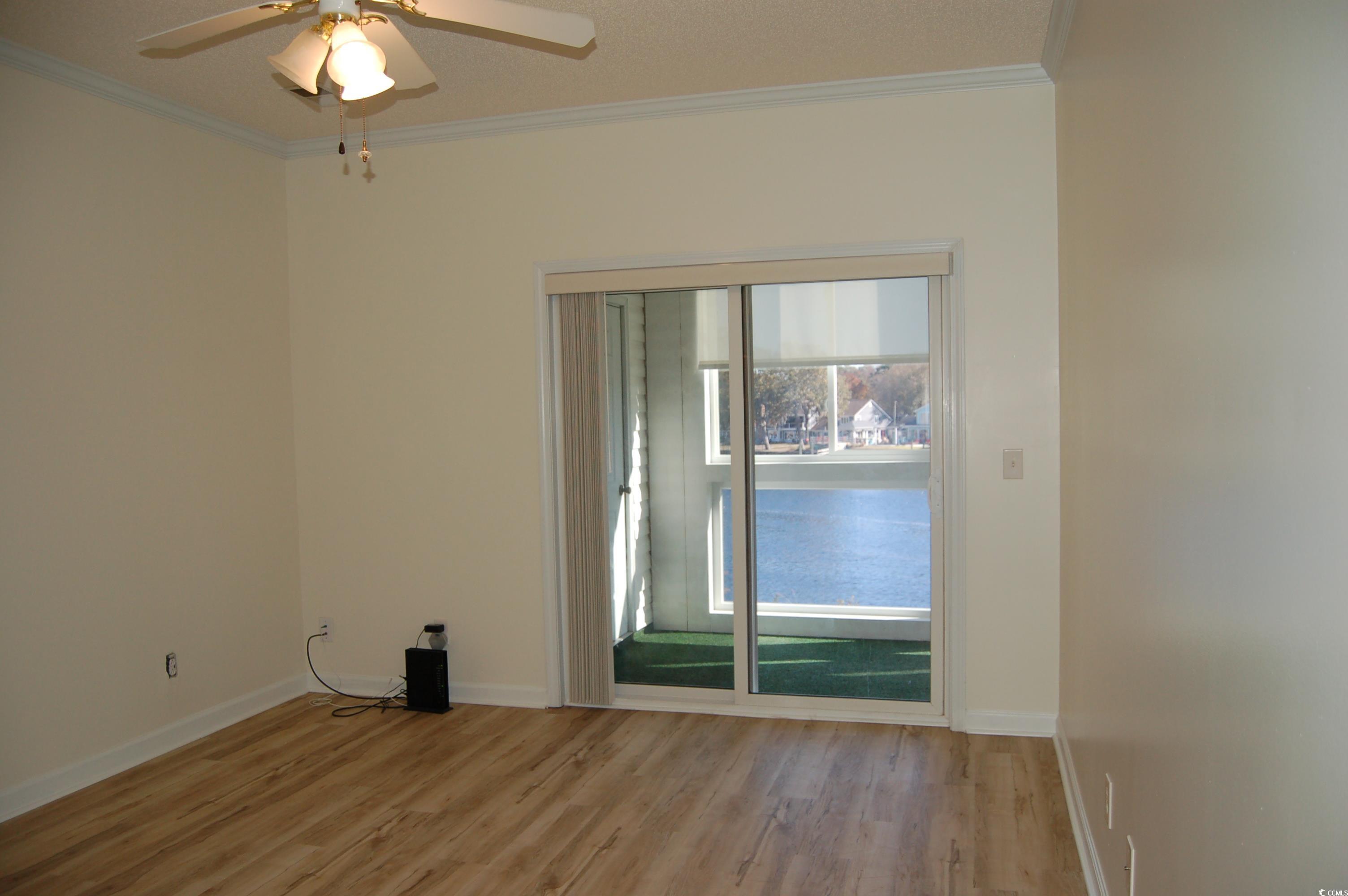 1537 Lanterns Rest Road, Unit 203 Myrtle Beach, SC 29579 - Photo 20 of 35 Unfurnished room with crown molding, light wood-style flooring, and ceiling fan with access to enclosed balcony