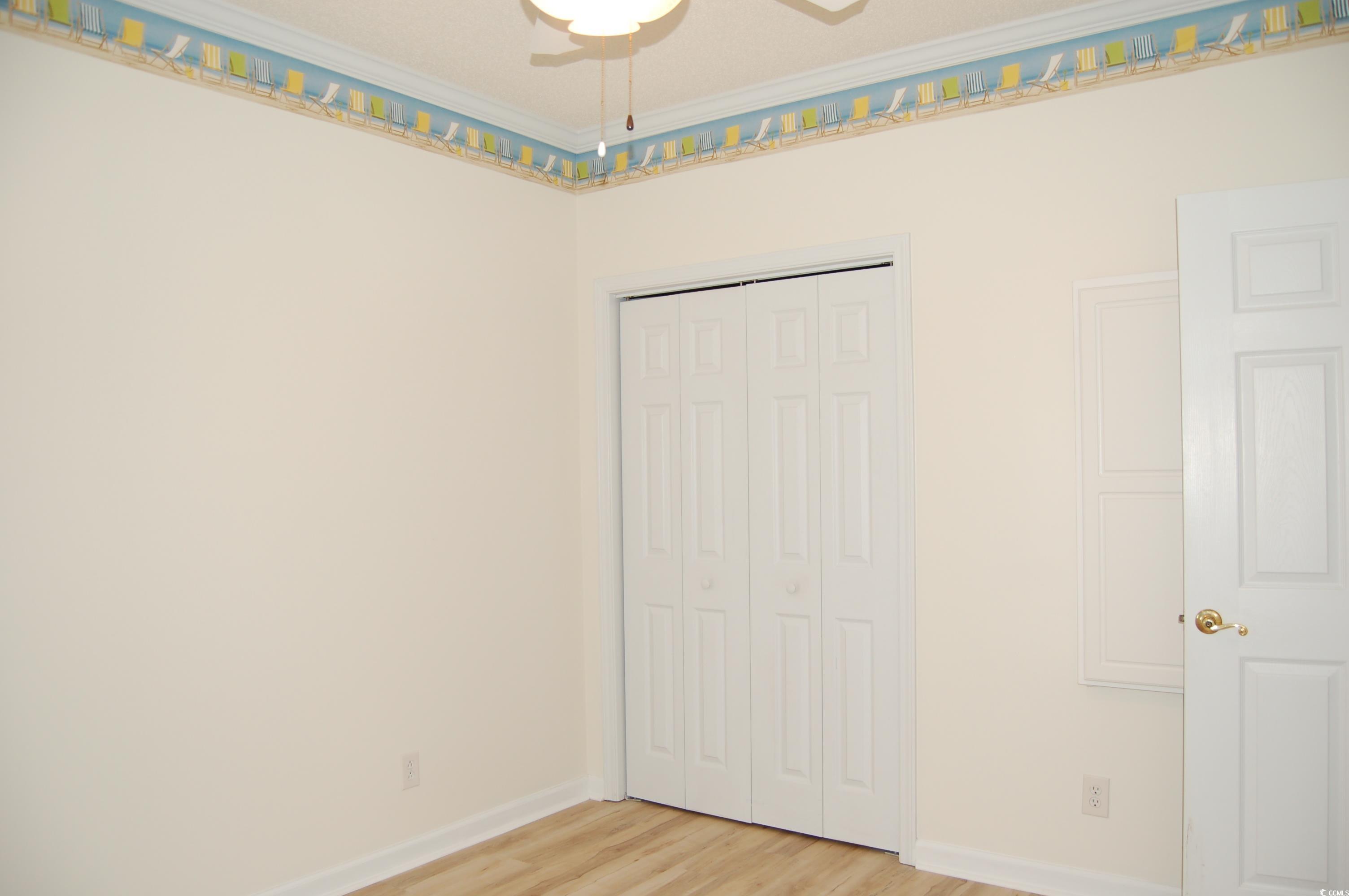 1537 Lanterns Rest Road, Unit 203 Myrtle Beach, SC 29579 - Photo 10 of 35 Unfurnished bedroom featuring light wood-style flooring, a closet, crown molding, and ceiling fan