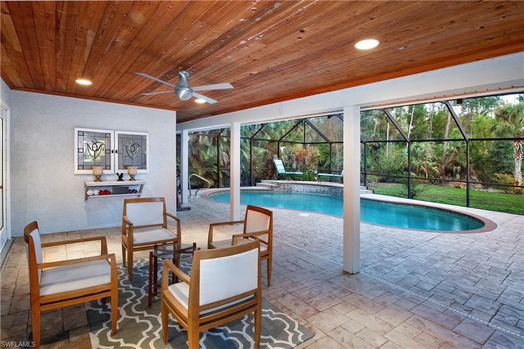 5340 Tamarind Ridge Drive Naples, FL 34119 - Photo 2 of 32 a living room with patio furniture and a floor to ceiling window