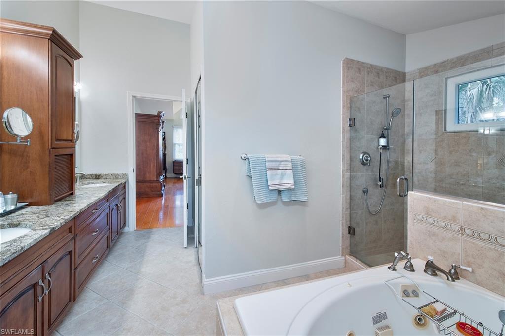 5340 Tamarind Ridge Drive Naples, FL 34119 - Photo 23 of 32 a bathroom with a tub sink and mirror
