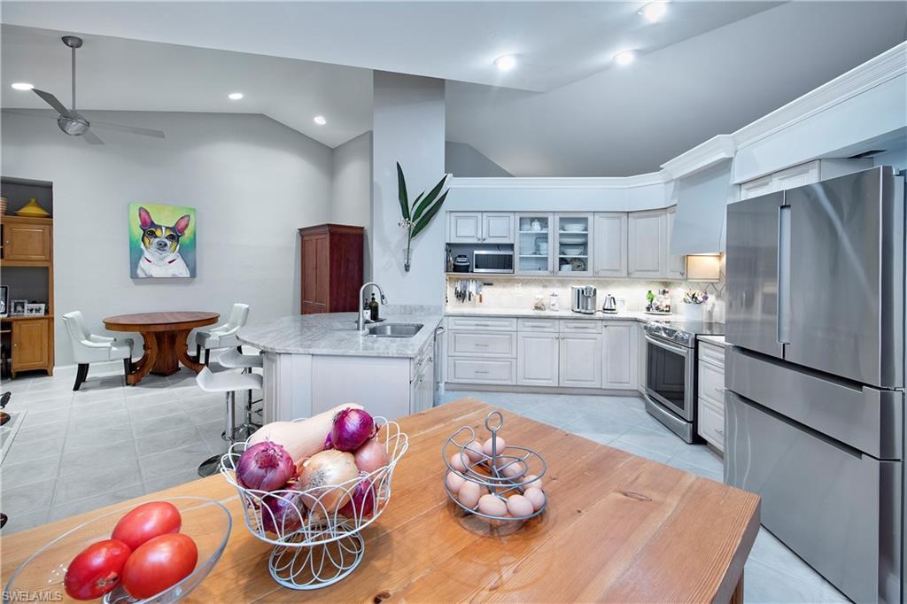 5340 Tamarind Ridge Drive Naples, FL 34119 - Photo 5 of 32 a kitchen with stainless steel appliances kitchen island granite countertop a sink dishwasher and cabinets with wooden floor