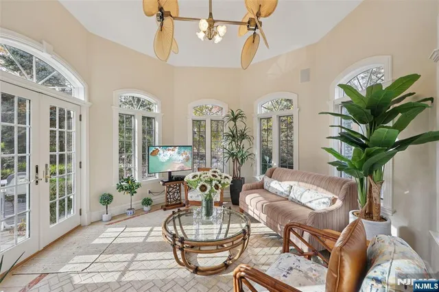a living room with furniture a chandelier and a dining table with garden view