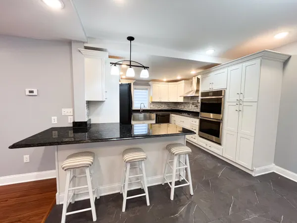 a kitchen with stainless steel appliances granite countertop a table chairs stove and refrigerator