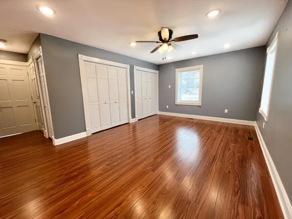 a view of empty room with wooden floor and fan