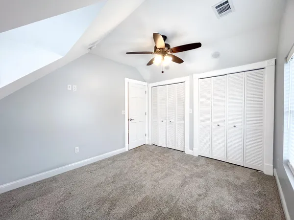 a view of empty room with windows and ceiling fan