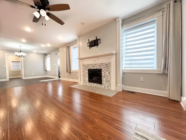 an empty room with wooden floor fireplace and windows