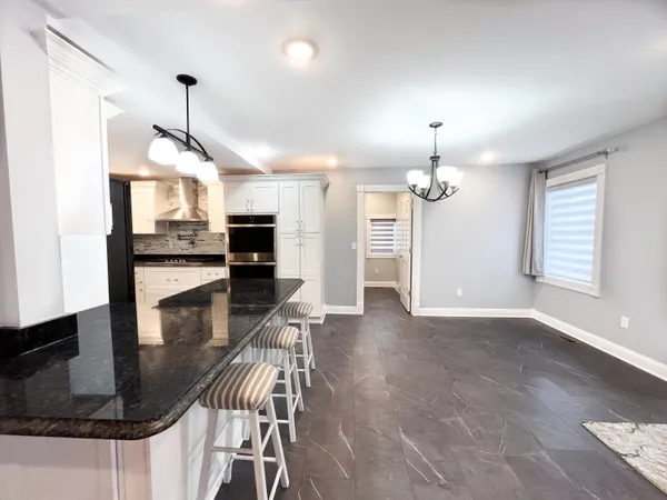 a view of a dining room and livingroom with furniture wooden floor a chandelier