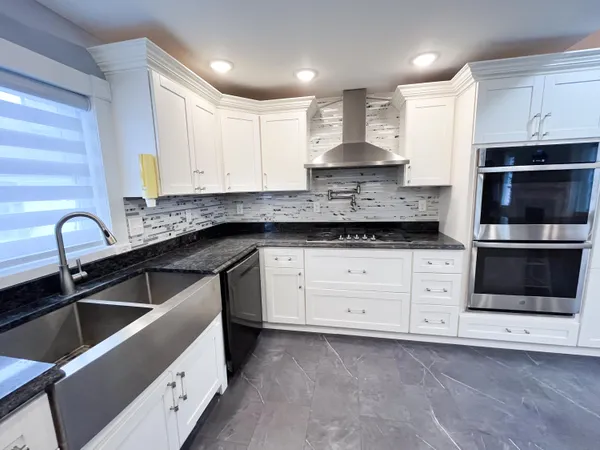 a kitchen with granite countertop white cabinets stainless steel appliances and a sink