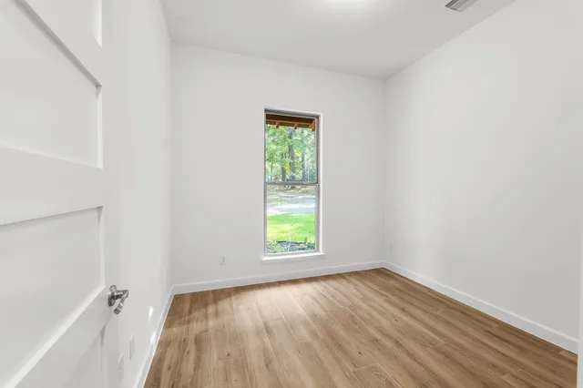 a view of an empty room with wooden floor and a window