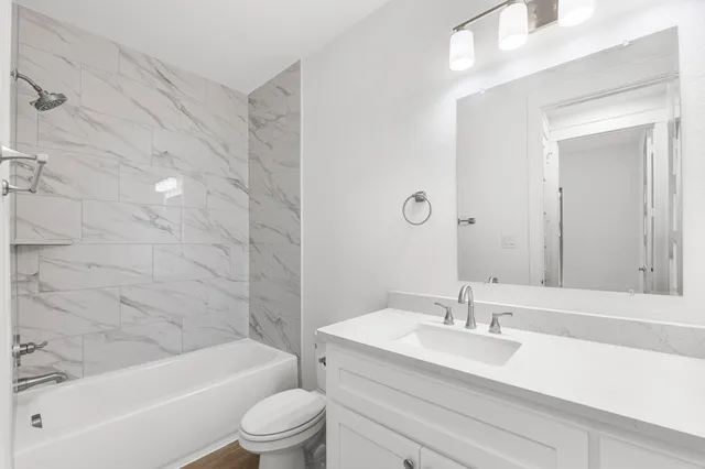 a bathroom with a granite countertop sink a toilet and bathtub