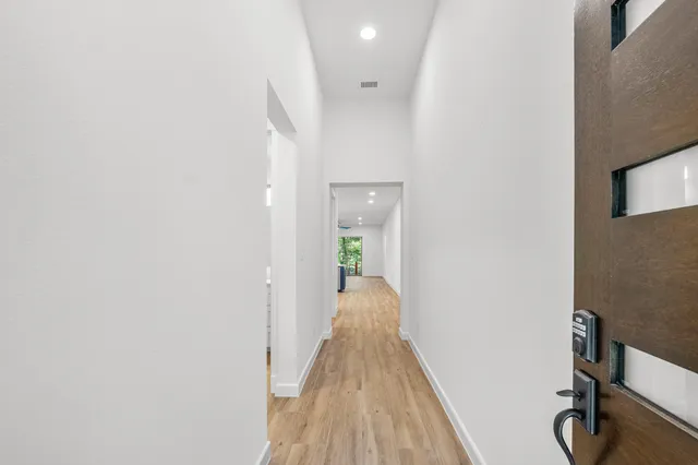 a view of a hallway with wooden floor and a bathroom