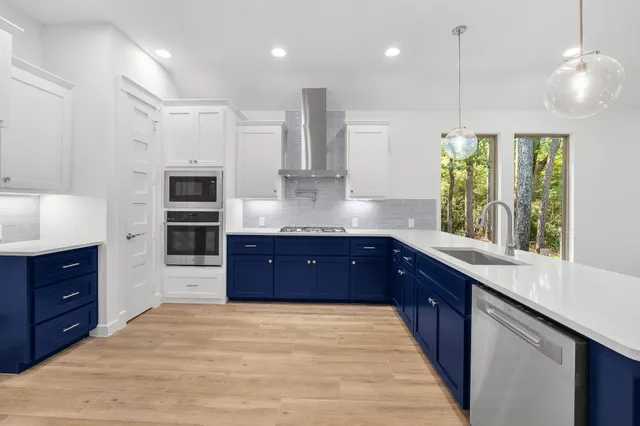 a kitchen with stainless steel appliances granite countertop a stove a sink and a refrigerator with wooden floor