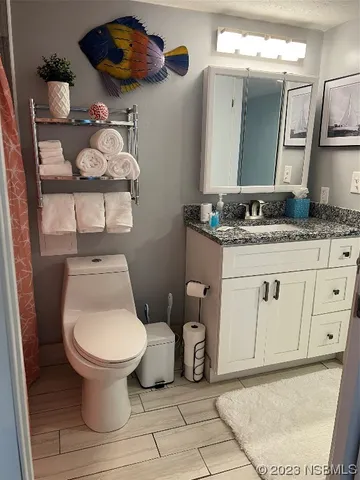 a bathroom with a granite countertop sink a toilet and a shower curtain