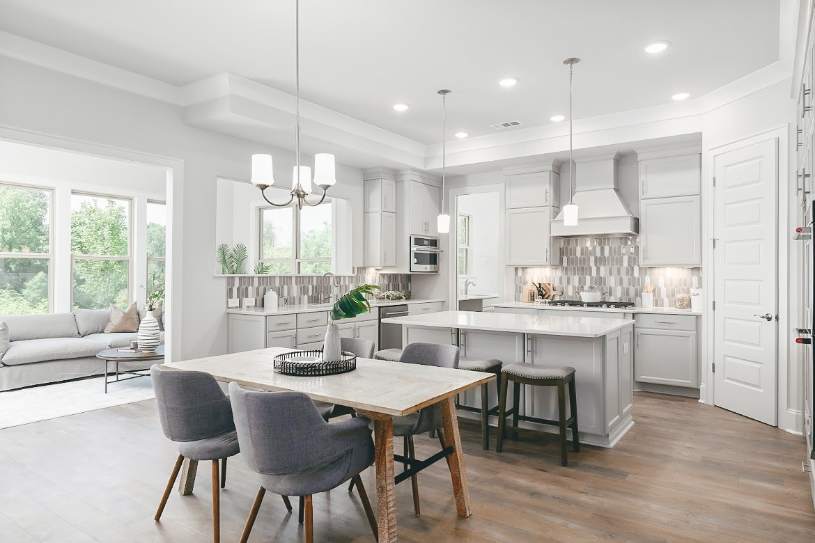 a kitchen with kitchen island granite countertop a table chairs sink and cabinets