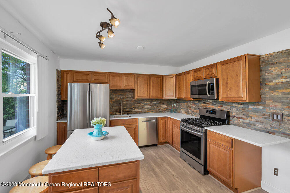 570 Labanna Court Brick, NJ 08724 - Photo 11 of 28 a kitchen with stainless steel appliances granite countertop a stove top oven a sink dishwasher a dining table and chairs with wooden floor