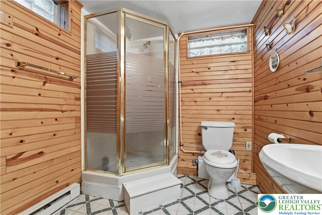 3303 Barklay Road Whitehall, PA 18052 - Photo 33 of 39 A corner shower enclosure and toilet complement the inviting warmth of horizontal wood paneling in this cozy bathroom.