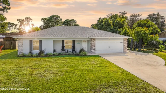 a front view of house with yard and trees in the background