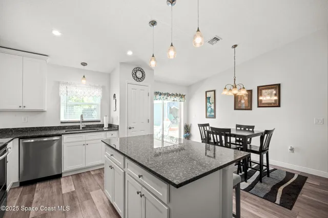a kitchen with stainless steel appliances granite countertop a kitchen island a stove a table and chairs
