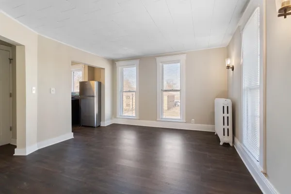 an empty room with wooden floor and windows with curtains view
