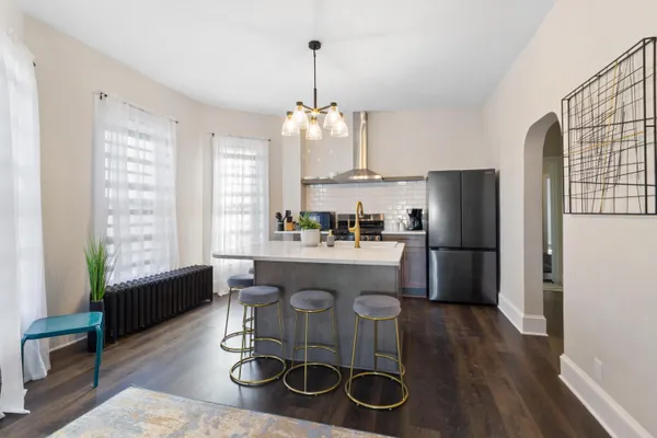 a kitchen with stainless steel appliances granite countertop a sink dishwasher a refrigerator a stove a dining table and chairs with wooden floor