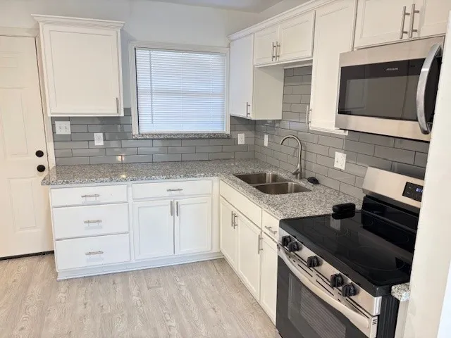 a kitchen with granite countertop a sink dishwasher stove and oven with wooden floor