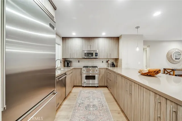 a large kitchen with stainless steel appliances lots of counter space and a sink