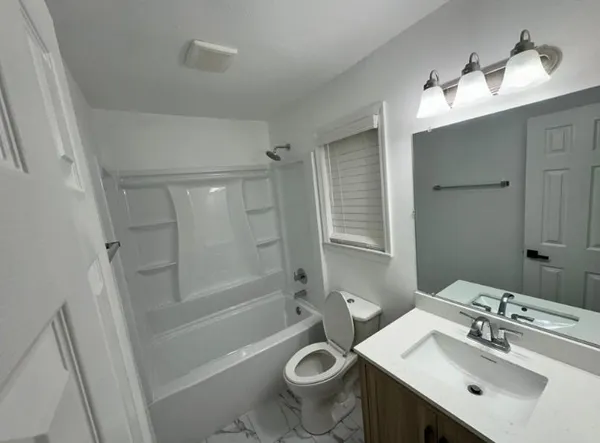 a bathroom with a sink a toilet a mirror a vanity and shower