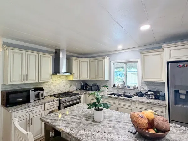 a kitchen with stainless steel appliances granite countertop a stove a sink a microwave and a refrigerator