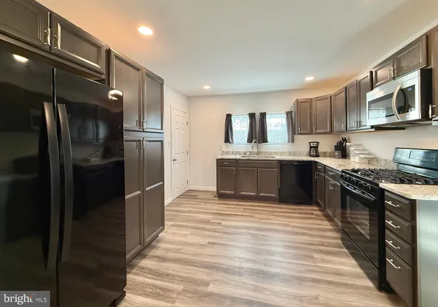 a large kitchen with stainless steel appliances granite countertop a stove a sink and a microwave