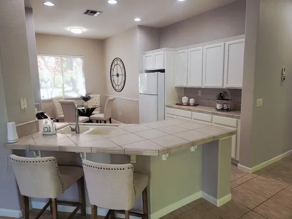 a kitchen with stainless steel appliances granite countertop a table chairs sink and cabinets