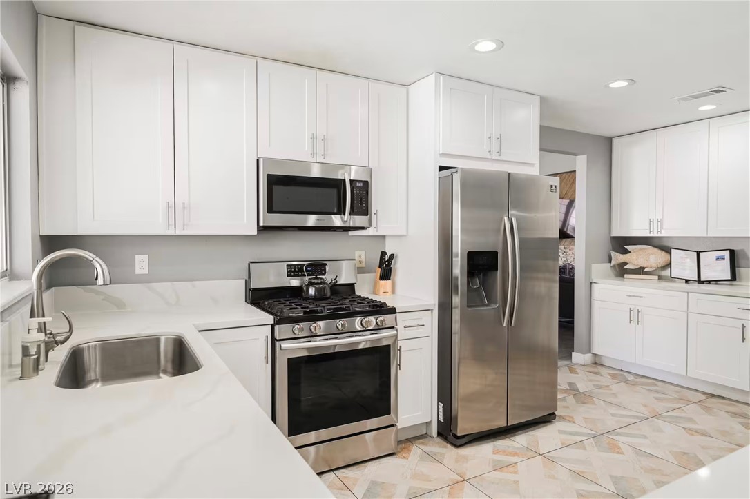 1803 Nuevo Road Henderson, NV 89014 - Photo 13 of 71 Kitchen featuring stainless steel appliances, white cabinetry, recessed lighting, and light stone counters