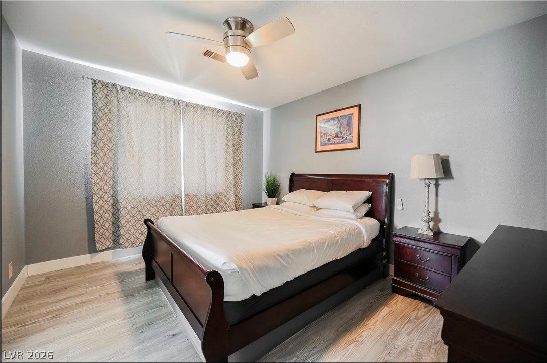 1803 Nuevo Road Henderson, NV 89014 - Photo 34 of 71 Bedroom featuring light wood-style floors, a ceiling fan, and a textured wall