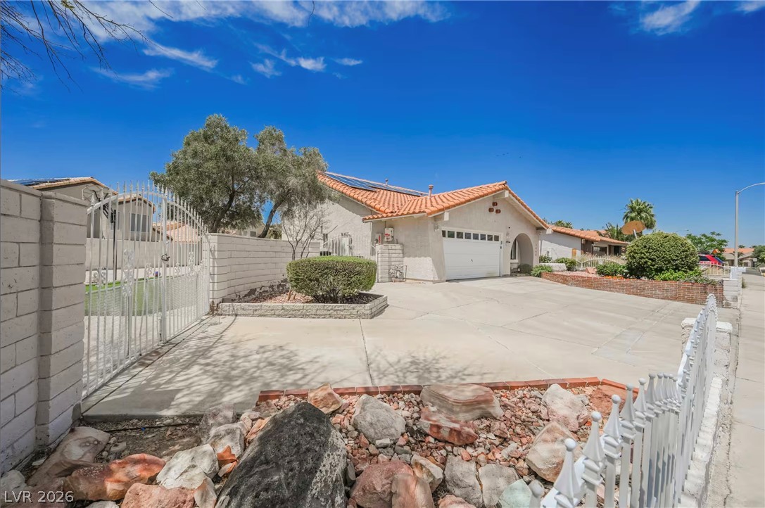 1803 Nuevo Road Henderson, NV 89014 - Photo 52 of 71 View of side of home featuring roof mounted solar panels, a garage, concrete driveway, a gate, and stucco siding