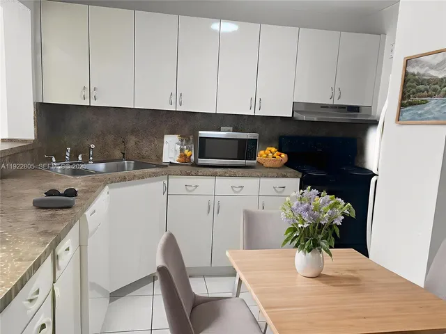 a kitchen with stainless steel appliances kitchen island granite countertop a table chairs in it and a window