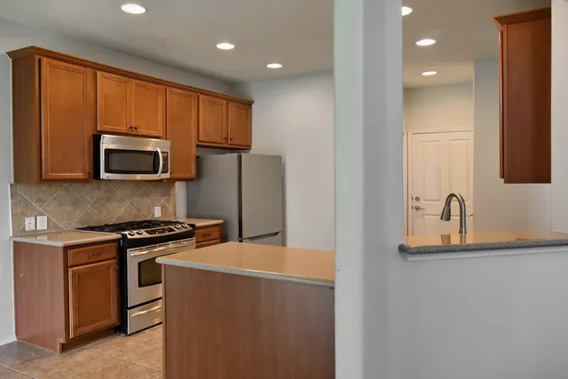 a kitchen with stainless steel appliances granite countertop a stove a sink and a microwave
