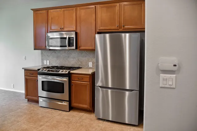 a kitchen with stainless steel appliances granite countertop a refrigerator a microwave a sink and cabinets