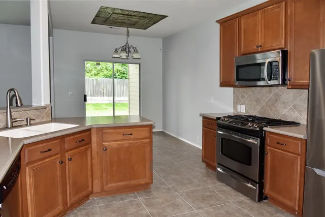 a kitchen with stainless steel appliances granite countertop a sink a stove a microwave and wooden cabinets