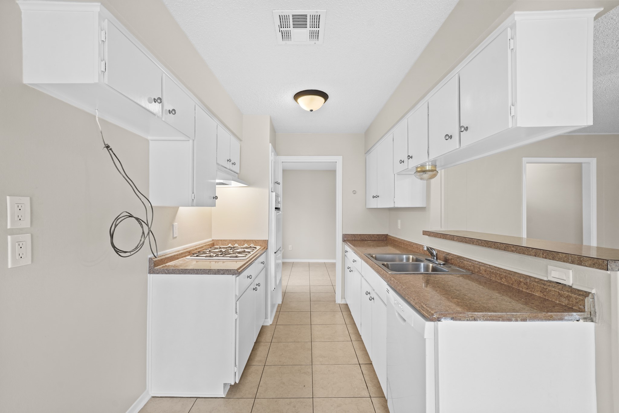 304 Cypress Street Alvin, TX 77511 - Photo 14 of 23 Functional galley kitchen with generous cabinetry, laminate countertops, double sink, gas cooktop, and adjacent dining access.