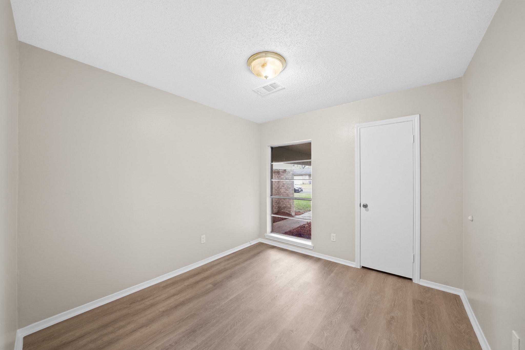 304 Cypress Street Alvin, TX 77511 - Photo 16 of 23 Bright galley-style kitchen with tile flooring, white cabinetry, ample counter space, and a view into the breakfast area with bay window.