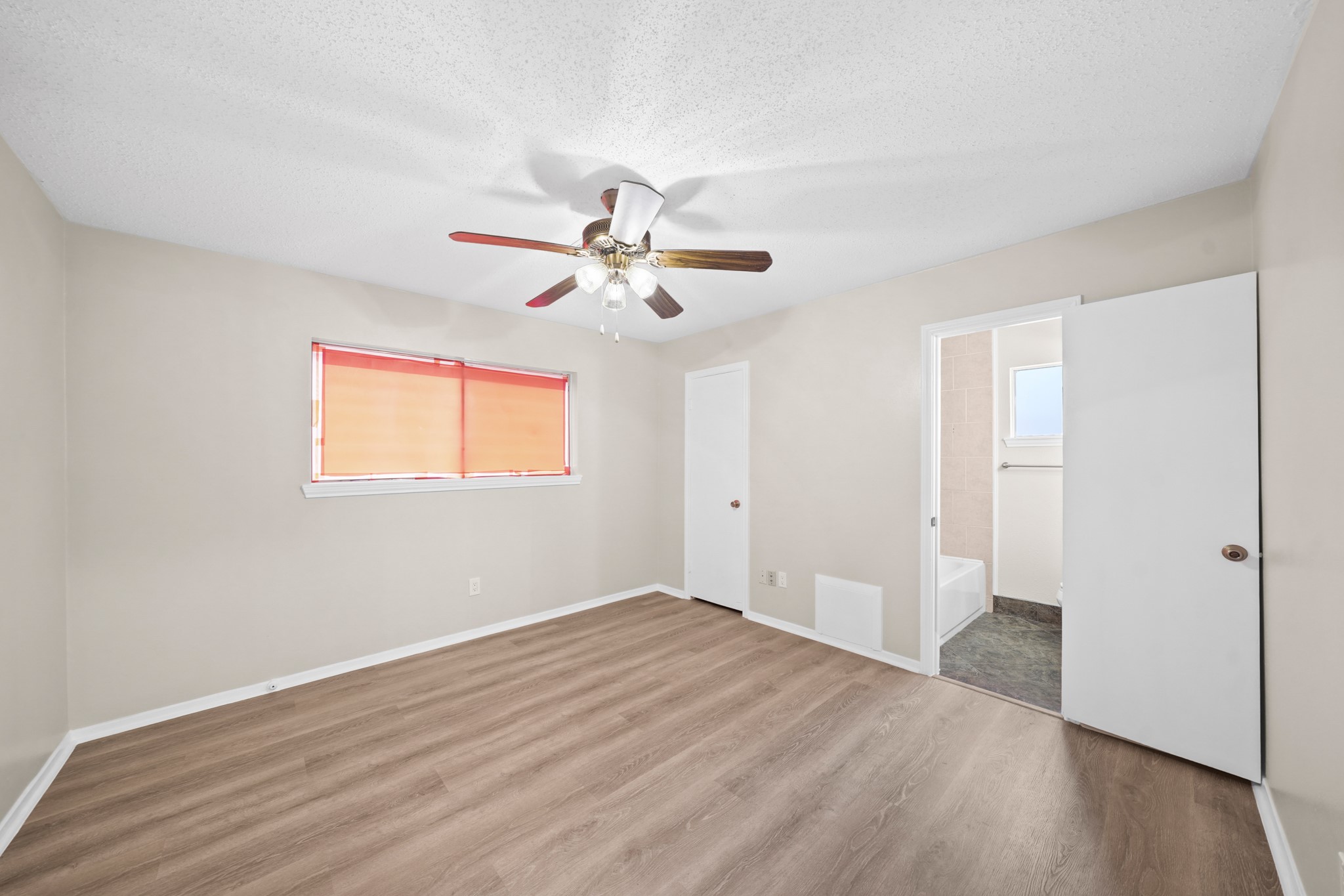 304 Cypress Street Alvin, TX 77511 - Photo 18 of 23 Spacious primary bedroom with wood-look flooring, ceiling fan, neutral paint, and private access to the ensuite bath.