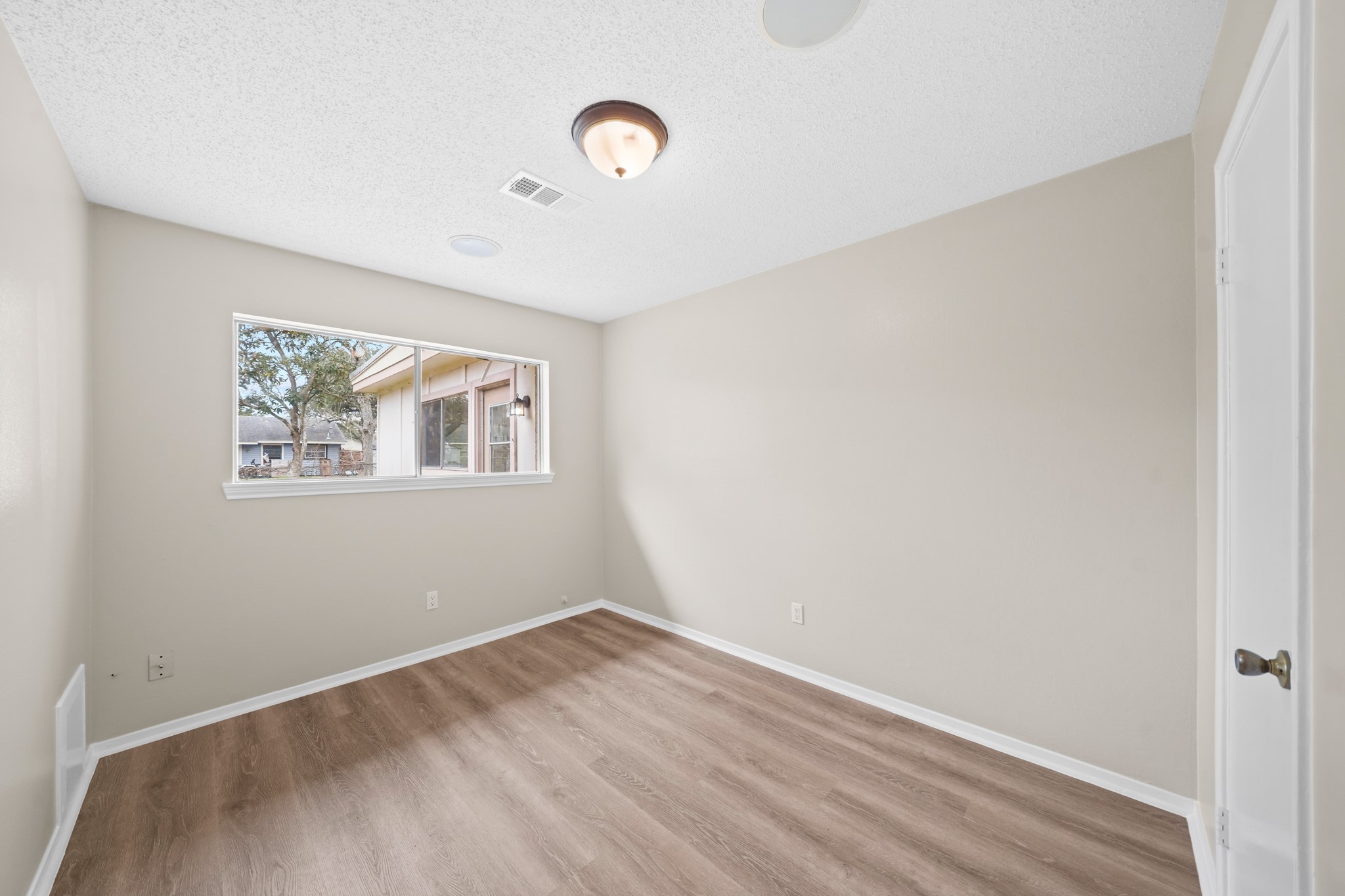 304 Cypress Street Alvin, TX 77511 - Photo 20 of 23 Bright secondary bedroom with wood-look flooring, neutral paint, and a window providing natural light.