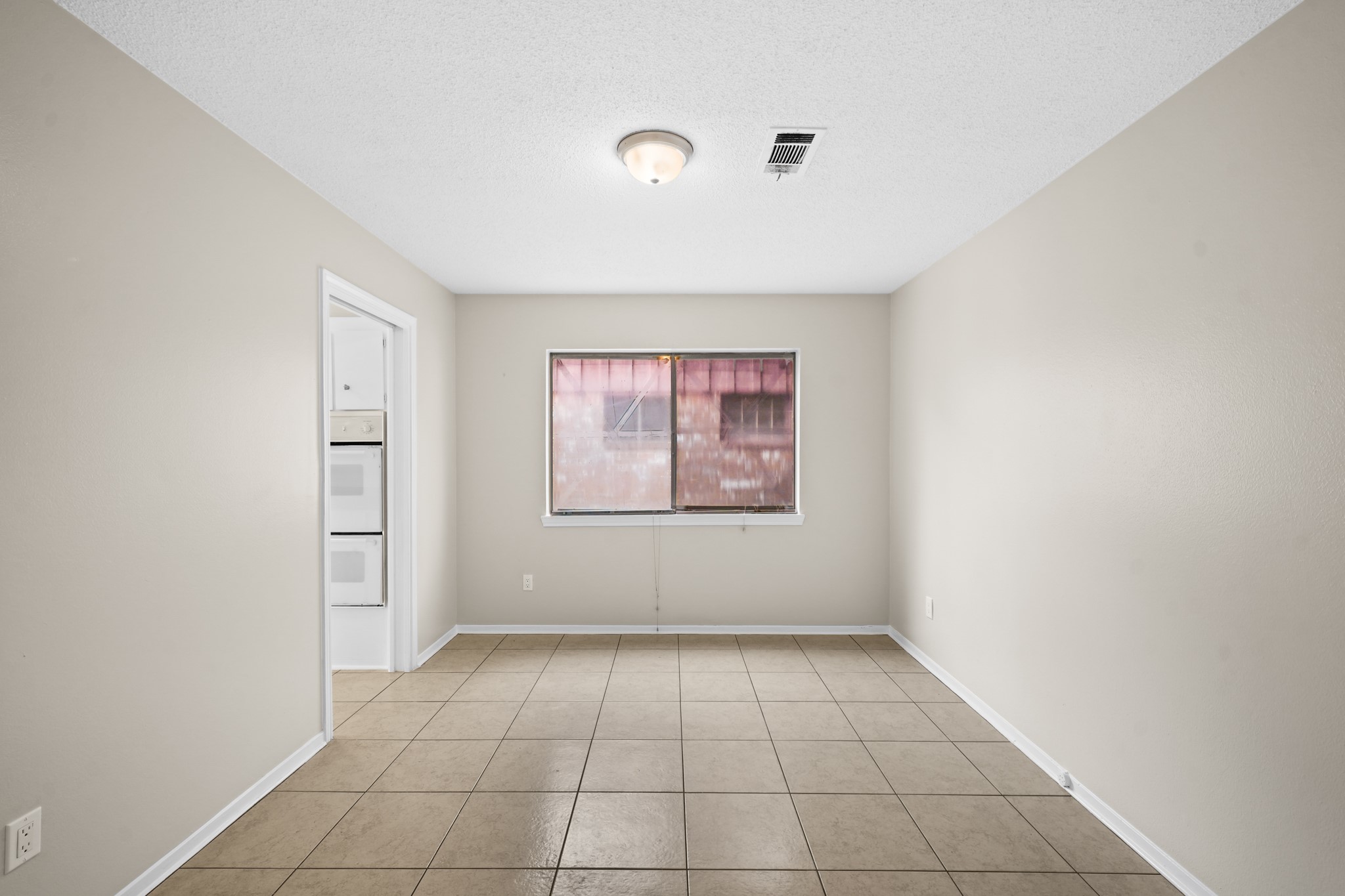 304 Cypress Street Alvin, TX 77511 - Photo 6 of 23 Spacious dining or flex area featuring tile flooring, neutral paint, and a large window that brings in natural light.