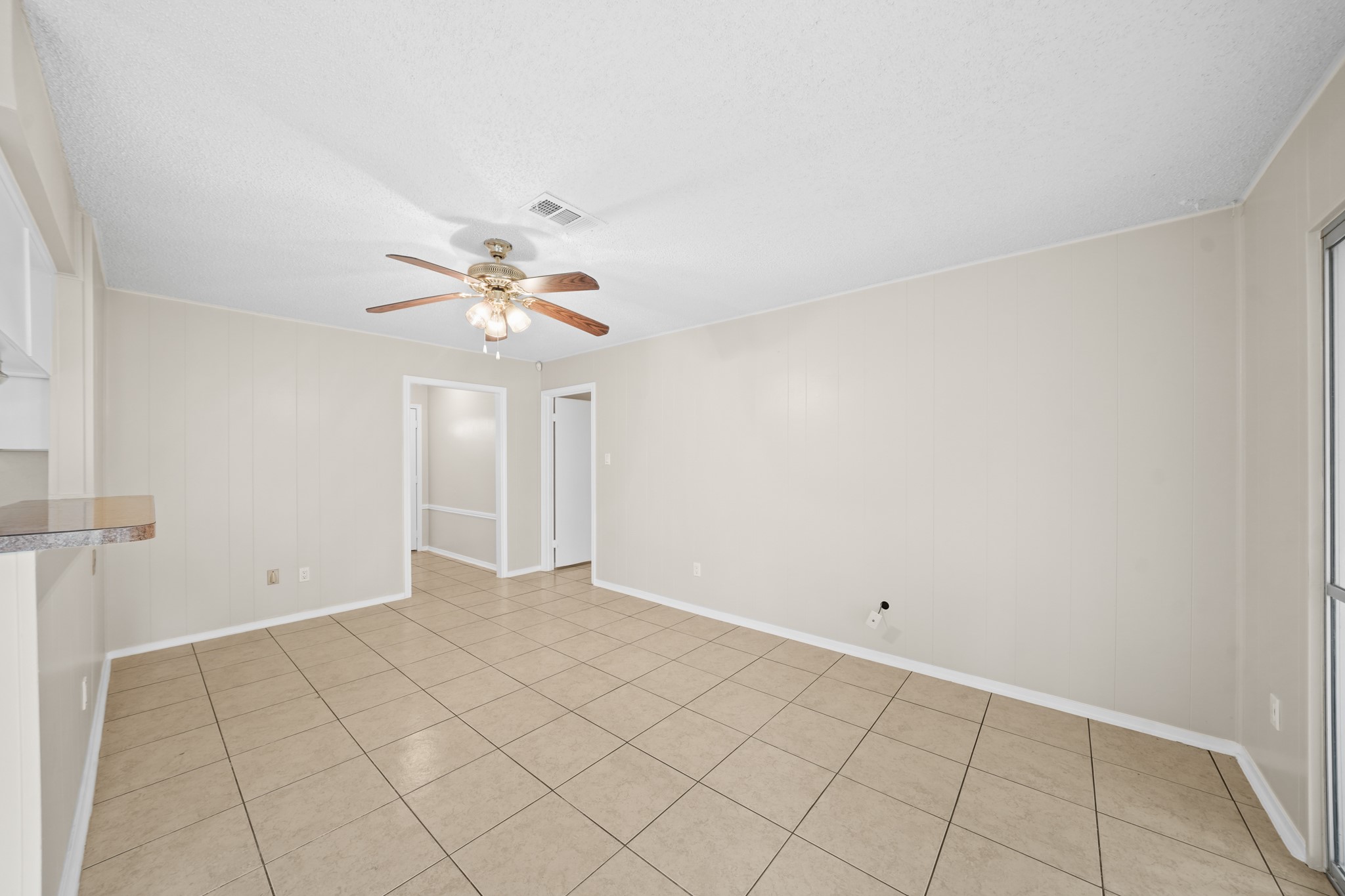 304 Cypress Street Alvin, TX 77511 - Photo 9 of 23 Large living space with tile flooring, neutral walls, ceiling fan, and open access to adjacent dining and entry areas.