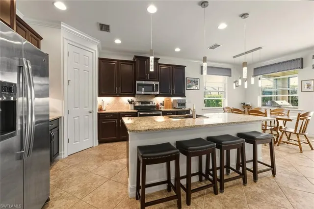 a kitchen with stainless steel appliances granite countertop a table chairs refrigerator and microwave