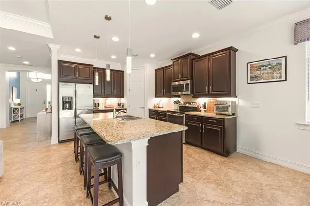 a kitchen with stainless steel appliances kitchen island granite countertop a sink refrigerator and cabinets
