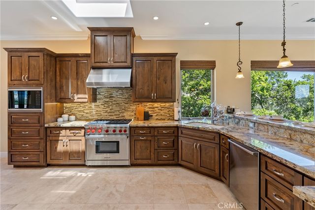 a kitchen with stainless steel appliances granite countertop a sink a stove and a wooden floors