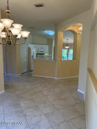 a view of a room with a chandelier fan and kitchen view