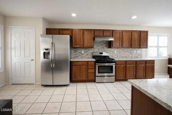 a kitchen with stainless steel appliances granite countertop a stove a sink and a refrigerator